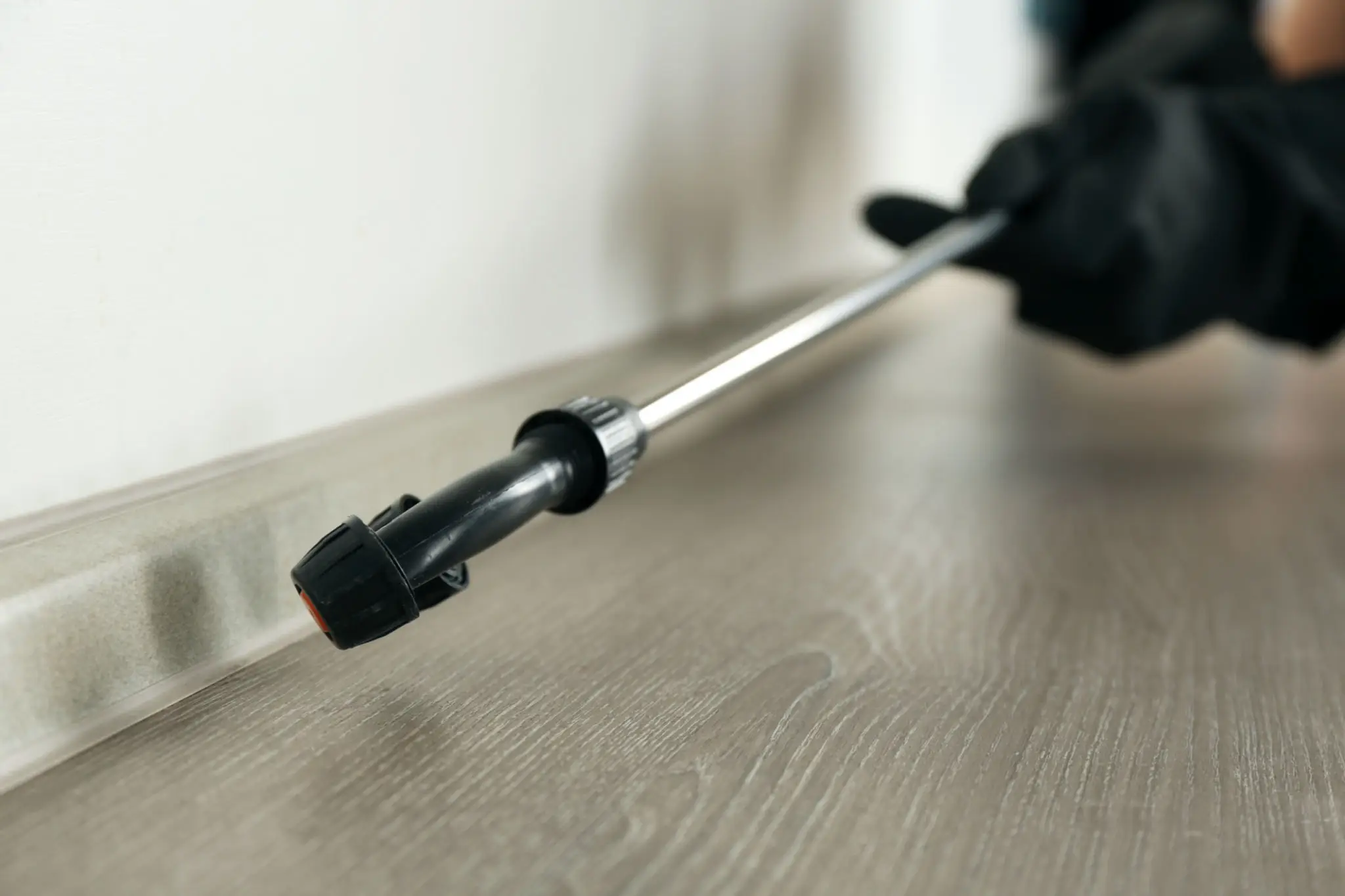 A close-up of a spray wand nozzle on a wooden floor.