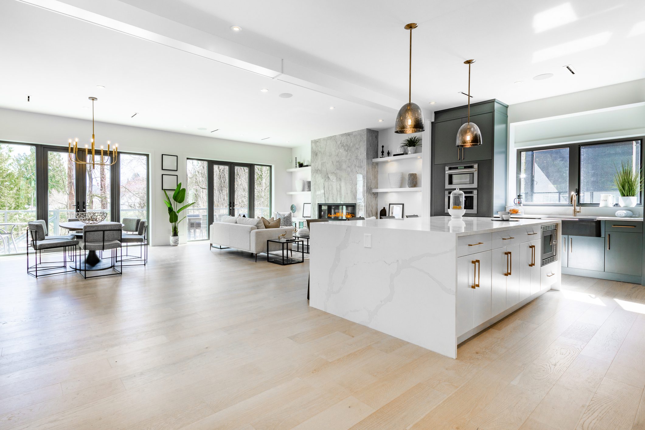 Bright modern kitchen with marble island and pendant lights.